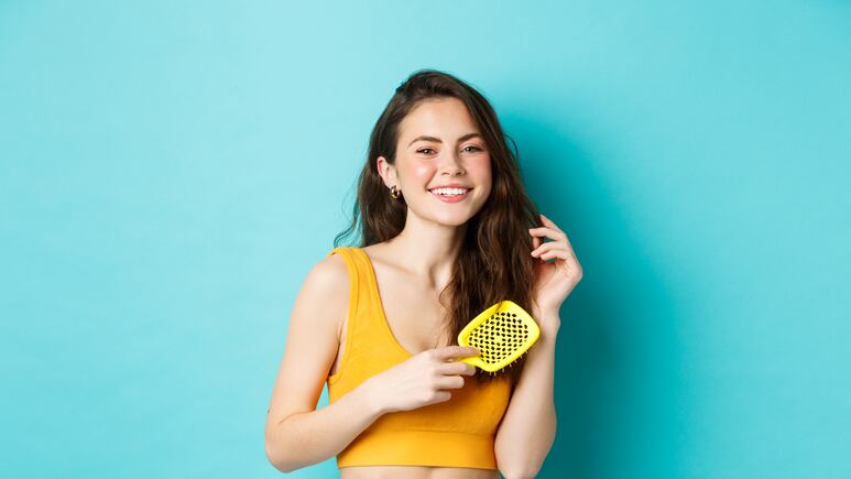 Joven desenredando cabello con cepillo